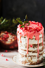 Festive honey cake with pomegranate seeds on wooden background