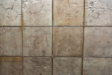 Textured tiled floor. Square beige tiles with patterns

