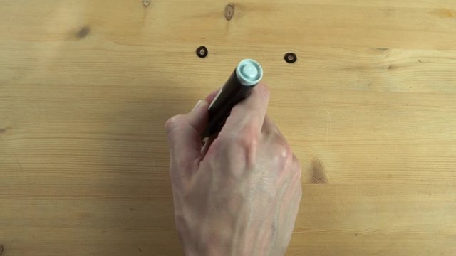 Man hand drawing and wipes out smiley face on wooden surface