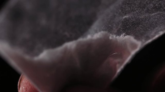 Flicking on a plastic bag with white powder.