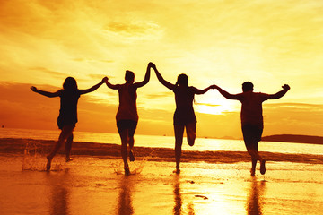 Fototapeta na wymiar Group of four happy friends at sunset beach