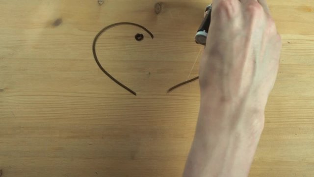 Male hand whipes out heart shape turned into kissing couple on wooden surface