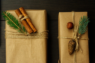 Gifts packed in kraft paper and decorated with spruce branches with cinnamon sticks of hazelnut and spruce cones. Gifts tied with ribbon. Rustic Style. Flat lay
