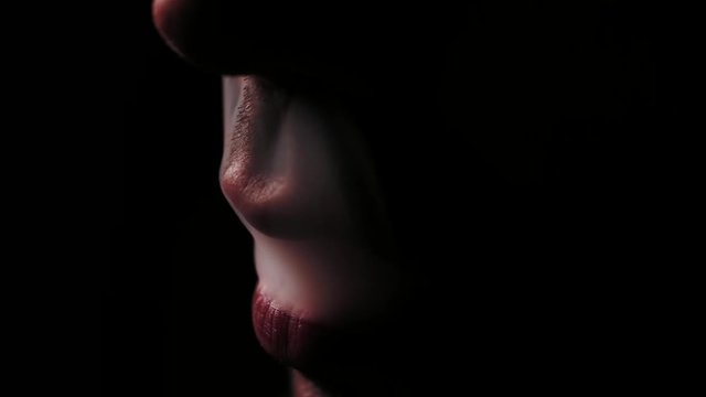 French inhale of a marijuana joint. Low key shot.