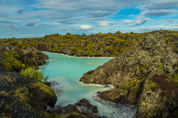 Obraz premium A pond with an unusually azure color of water. A beautiful sky with clouds. Blue Lagoon. Iceland. Geothermal lake, a unique place. 