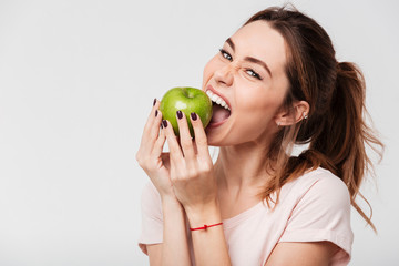 Close up of a hungry funny girl biting an apple