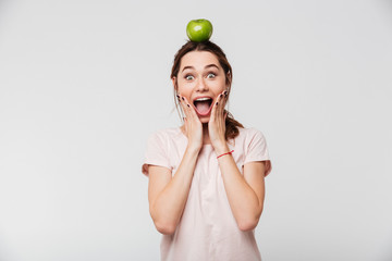 Portrait of an excited girl holding apple on her head