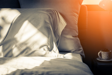 Bed maid-up with clean white pillows and bed sheets in bedroom. Close-up. Lens flair in sunlight.