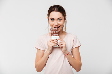 Portrait of a smiling pretty girl eating chocolate bar
