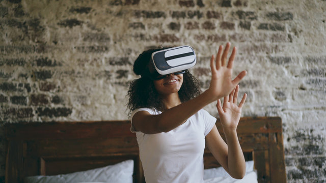 Curly african american woman getting experience using VR 360 headset glasses of virtual reality at home