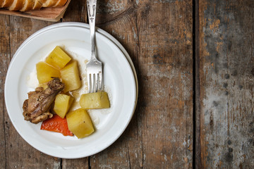 chicken meat stewed with potatoes, carrots and spices in a cast-iron pot on a wooden background