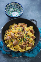 Pilaf with pork meat and mushrooms in a cast-iron pan, vertical shot