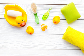 Baby bath set with yellow rubber duck. Soap, sponge, brushes, towel on white wooden background top view copyspace