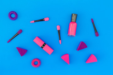 Bright decorative cosmetics. Pink nail polish and lipstick on blue background top view