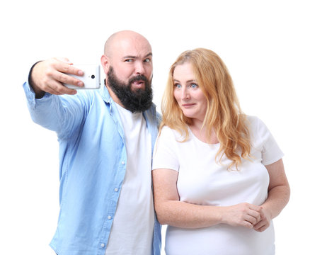 Overweight couple taking selfie on white background