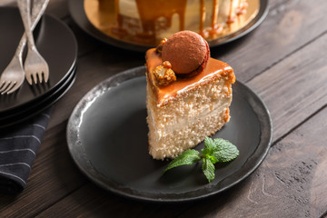 Plate with piece of delicious caramel cake on table