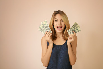 Happy young woman with dollar banknotes on color background