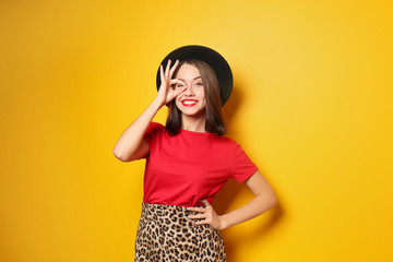 Attractive hipster girl in hat on color background