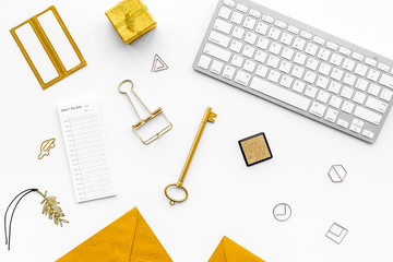 Fashoin in the workplace. Office desk in a trendy gold color. Stationery near keyboard on white...