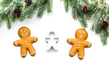 Gingerbread man cookies for New Year meal near spruce branch on white background top view