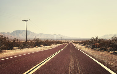 Fototapeta premium Retro old filmy stylized picture of an empty road, USA.