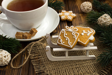 Christmas cookies on the sledges and tea on the wooden background