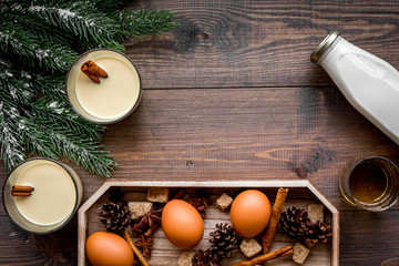 Make eggnog classic recipe. Eggs, milk, cinnamon, whiskey on dark wooden background top view copyspace