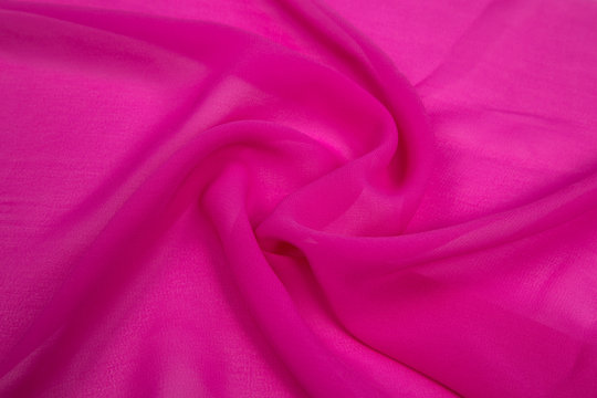 bright pink square and the light fabric spread out in soft folds on the table