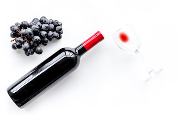 Taste red wine. Bottle of red wine, glass and black grape on white background top view copyspace