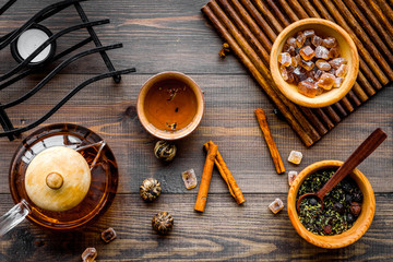 Tea ceremony concept. Tea pot, cups, dry tea leaves, sugar on dark wooden background top view
