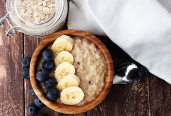 Bowl of oatmeal porridge with banana, blueberries on rustic table, hot and healthy food for Breakfast