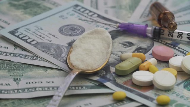 Drugs and pills for addiction lie on the thousands of paper dollars 