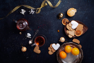Teatime with heart-shaped ginger cookies and tangerines. Christmas background with festive decoration. Horizontal composition