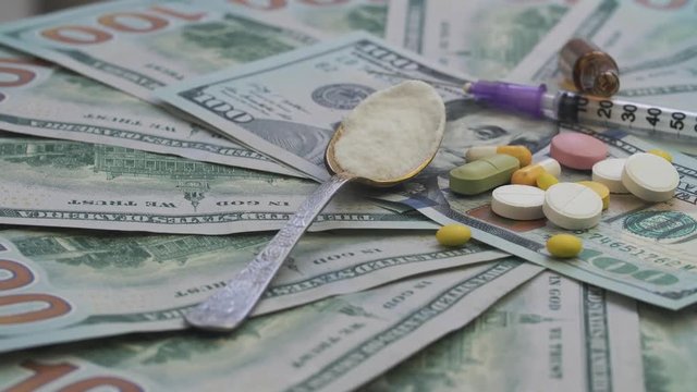 Drugs and pills for addiction lie on the thousands of paper dollars 