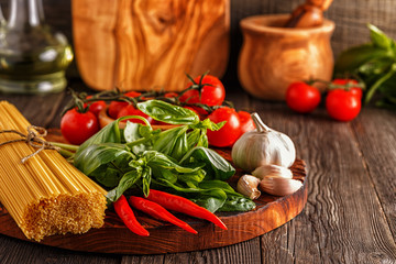 Products for cooking - pasta, tomatoes, garlic, pepper, and basil.