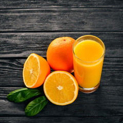 Orange fresh juice and oranges on a wooden surface. Top view. Free space for text.