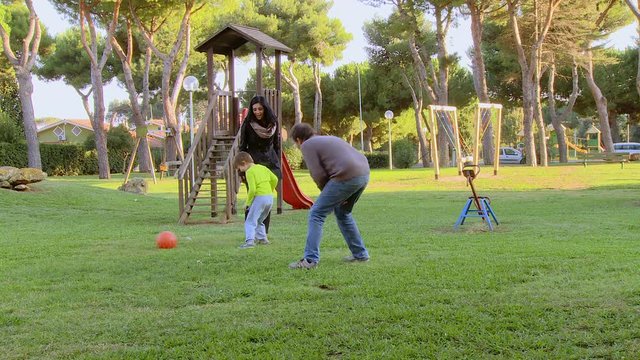 Father mother son playing soccer in park