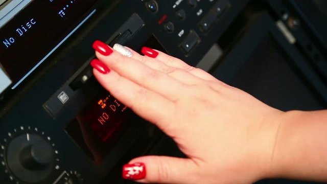A female right hand inserts a mini disc into the player. Close-up