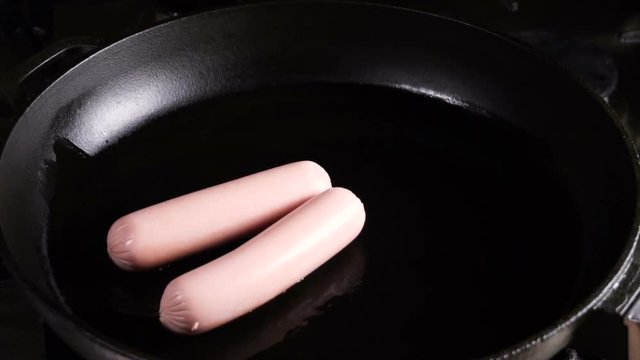 Sausages fried with tomatoes and eggs, the process of cooking. Breakfast.