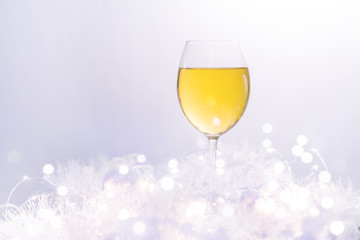 Wineglass of white wine on a white blurred background. Blurred bokeh light background, Christmas and New Year holidays background. Soft focus.