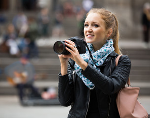 woman walking in autumn city with digital camera