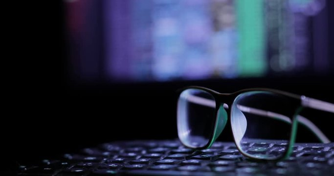 glasses on the keyboard, on the background of the monitor