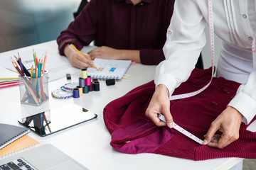 Two young professional Fashion designer colleagues working and project of drawing sketches for clothes in workplace with laptop, digital tablet and color charts, Fashion Designer Stylish Concept