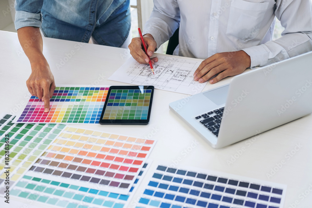 Poster Two interior design or graphic designer at work on project of architecture drawing with work tools and color swatches, colour chart, color samples for selection, renovation and technology concept