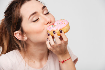 Close up portrait of a pleased pretty girl eating donuts