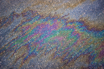 Gasoline flows on the asphalt surface. Iridescent stains of gasoline.