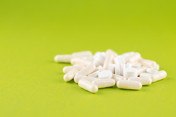 Close up white pills and capsules on pear yellow background with copy space. Focus on foreground, soft bokeh. Pharmacy drugstore concept