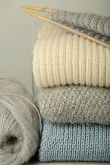 Handmade, knitting and woolen thread. Pile of knitted clothes blue, white and gray colors.