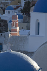 Sunlit church spire and blue domes Oia Santorini Greece