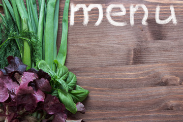 Word menu on the background of wood and fresh herbs. Background for the seasonal menu. Top view.